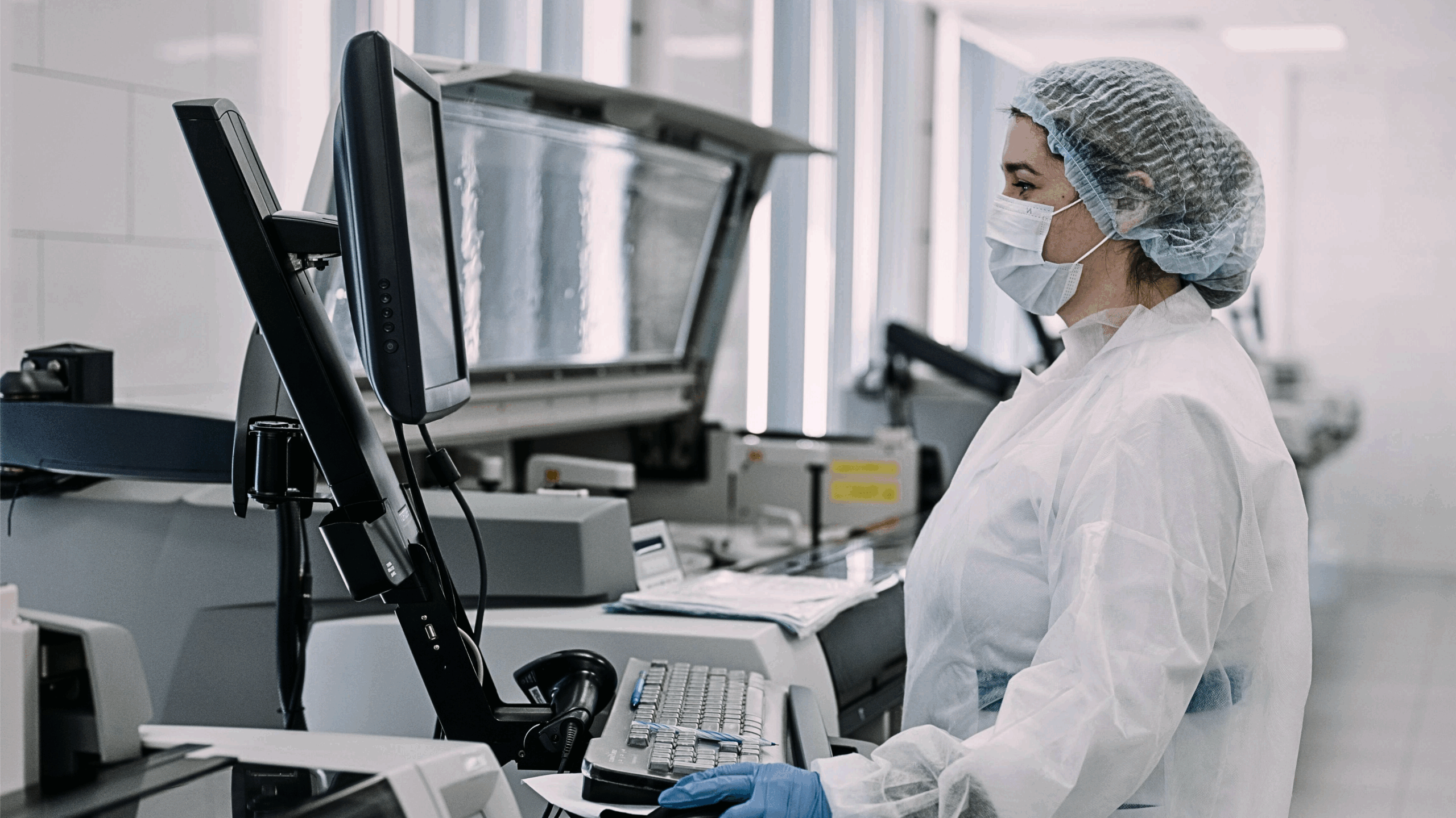 Worker in disposable personal protection equipment works at a piece of equipment in a biomanufacturing facility.