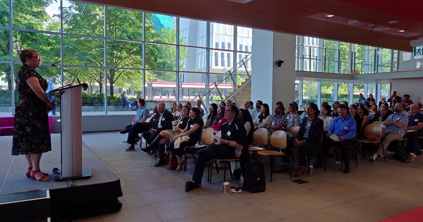 Patrycja Thompson speaking at the podium at the Toronto Cell Therapy Symposium.